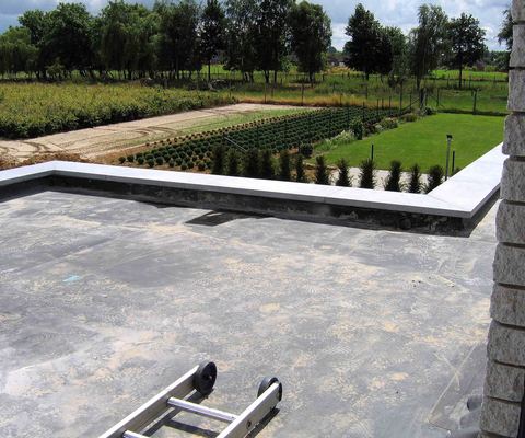 Finished black rubber membrane covering a flat roof behind a stone parapet
