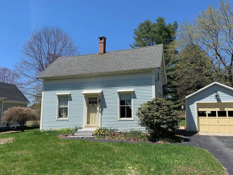 Pale blue New England cape house with a gray shingle roof, chimney and garage